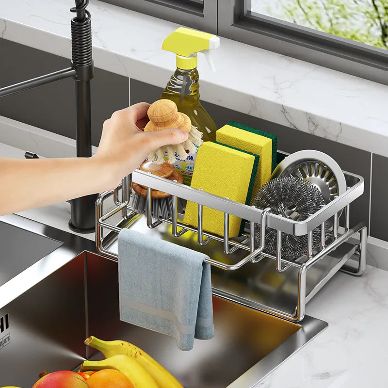 Stainless steel kitchen sink organizer holding a sponge, soap and dishcloth